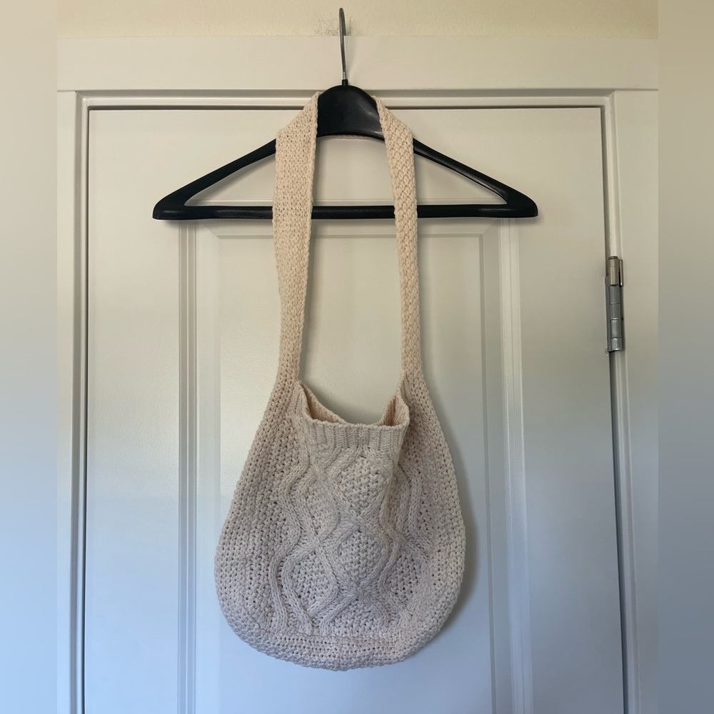 Cream knit bag with a long strap and snap button closure